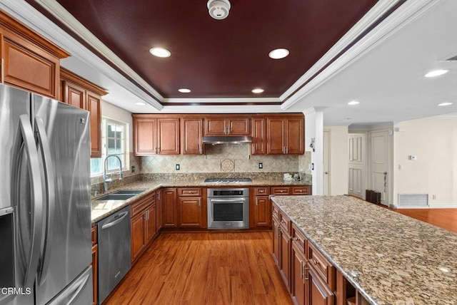 kitchen featuring decorative backsplash, ornamental molding, light stone counters, stainless steel appliances, and light hardwood / wood-style flooring