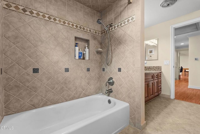 bathroom featuring tile patterned flooring, vanity, and tiled shower / bath