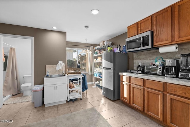 kitchen featuring tasteful backsplash, an inviting chandelier, decorative light fixtures, light tile patterned floors, and appliances with stainless steel finishes