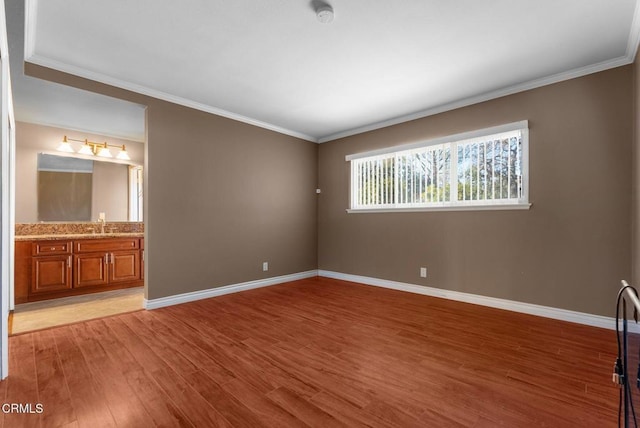 unfurnished bedroom featuring connected bathroom, crown molding, and hardwood / wood-style flooring