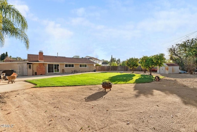 view of yard with a shed and an outdoor fire pit