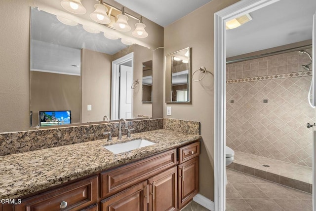 bathroom featuring vanity, tile patterned floors, toilet, and a tile shower