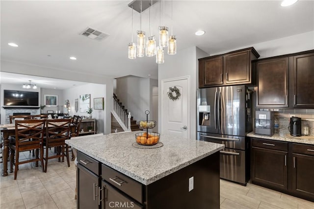 kitchen with a fireplace, hanging light fixtures, a center island, stainless steel fridge with ice dispenser, and dark brown cabinets