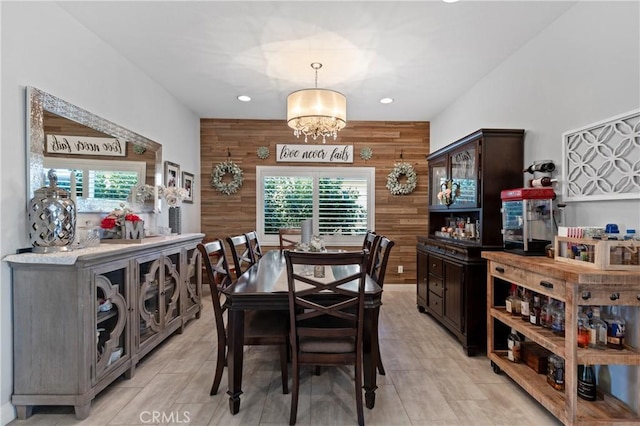 dining space featuring a chandelier and wooden walls