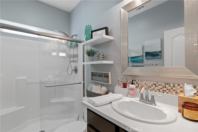 bathroom with tasteful backsplash, vanity, a shower with shower door, and toilet