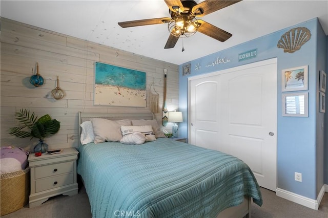 carpeted bedroom with wooden walls, ceiling fan, and a closet