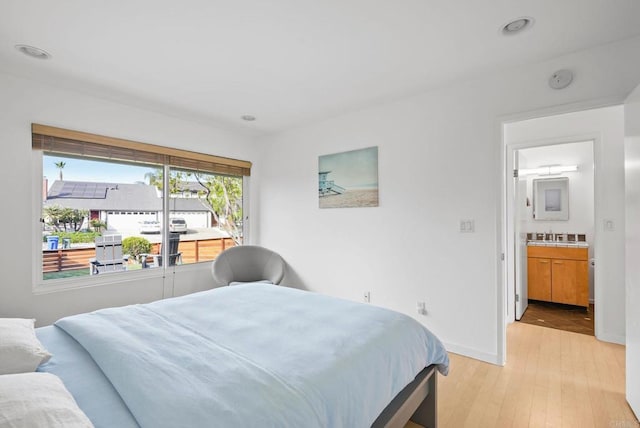 bedroom featuring ensuite bath and light hardwood / wood-style floors