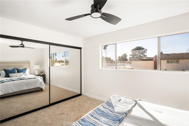 carpeted bedroom with a closet, baseboards, and ceiling fan