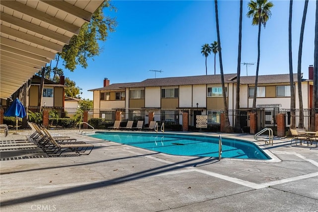 community pool with a patio and fence