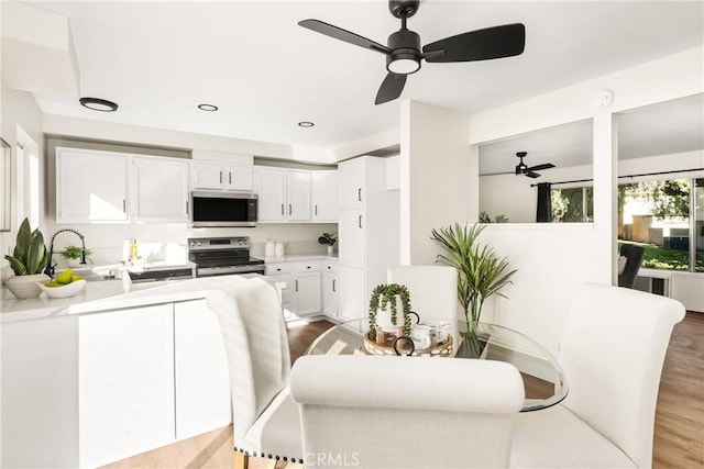 dining space with light wood-style flooring and ceiling fan