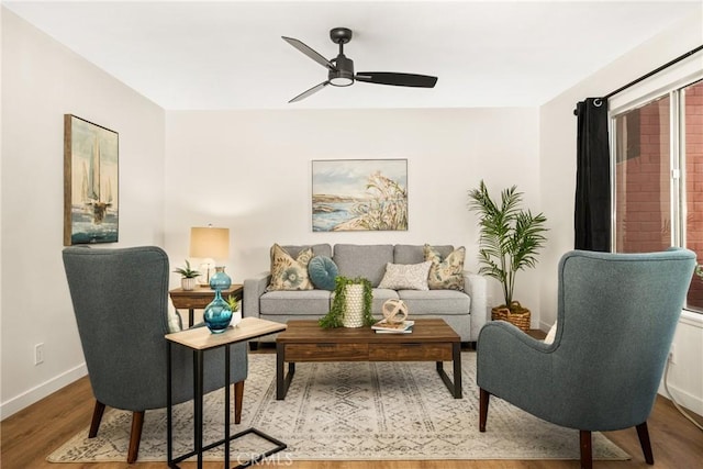 living room featuring baseboards, wood finished floors, and a ceiling fan