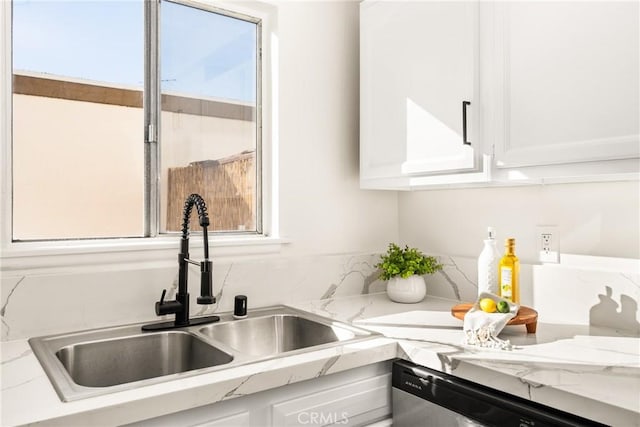 kitchen with white cabinets, light stone countertops, stainless steel dishwasher, and a sink