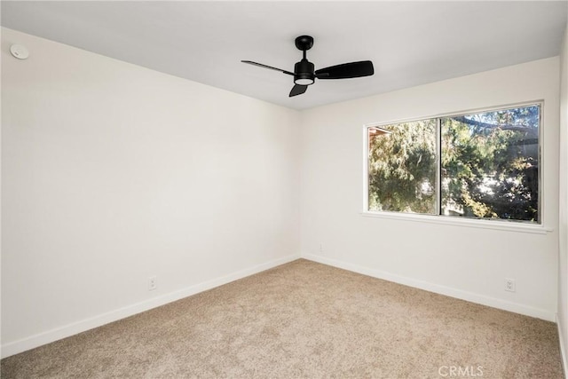 carpeted spare room with a ceiling fan and baseboards