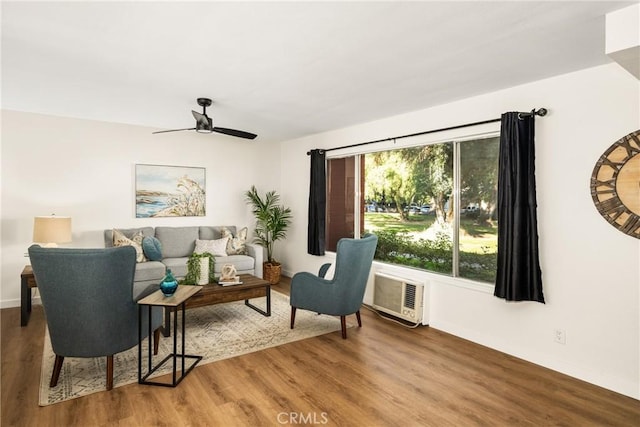 living room featuring baseboards, a wall mounted air conditioner, ceiling fan, and wood finished floors