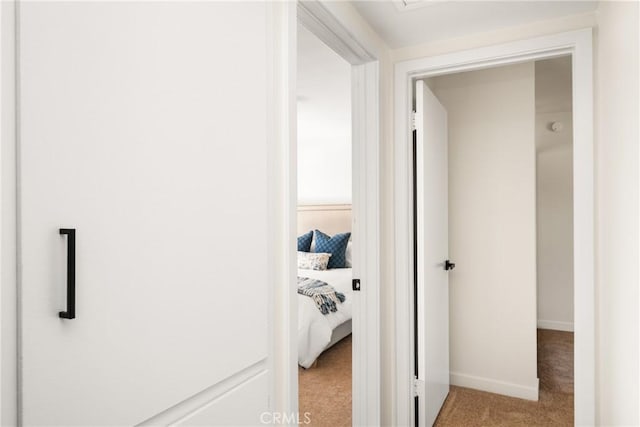 corridor featuring baseboards and light colored carpet