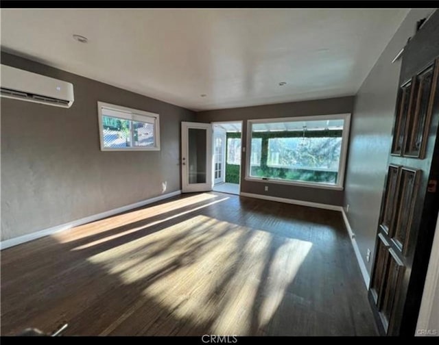 unfurnished living room with dark hardwood / wood-style floors and a wall unit AC