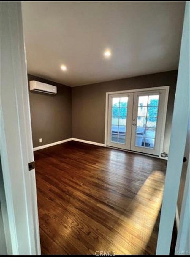 unfurnished room with dark wood-type flooring, a wall mounted air conditioner, and french doors