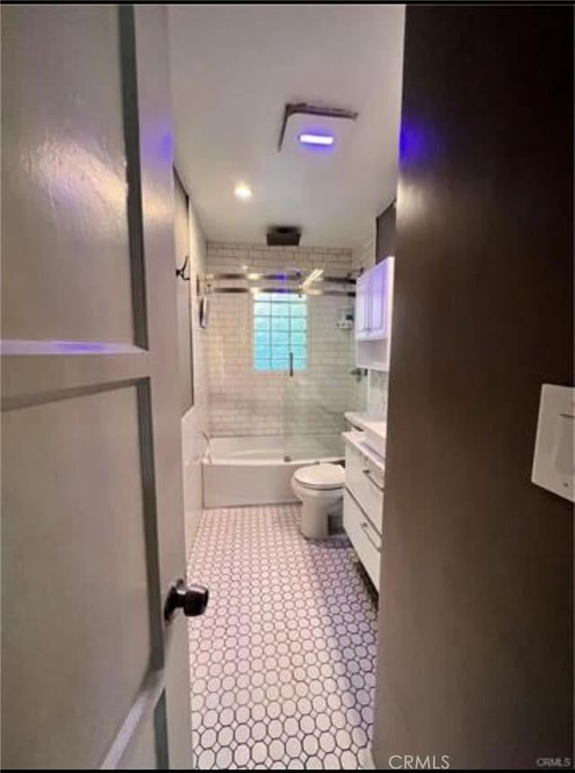 full bathroom featuring tiled shower / bath, vanity, and toilet