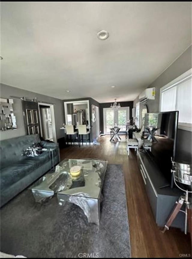 living room featuring a wall unit AC, dark hardwood / wood-style floors, and a chandelier