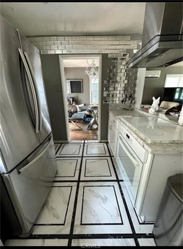 kitchen with stainless steel fridge, extractor fan, light stone countertops, white cabinets, and oven