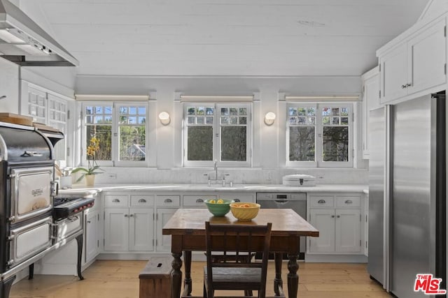 kitchen featuring white cabinetry, stainless steel appliances, tasteful backsplash, and wall chimney range hood