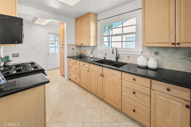 kitchen with sink, dark stone countertops, backsplash, light brown cabinets, and gas range oven