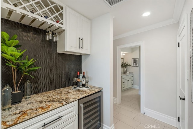 bar with light tile patterned flooring, white cabinetry, beverage cooler, crown molding, and light stone countertops