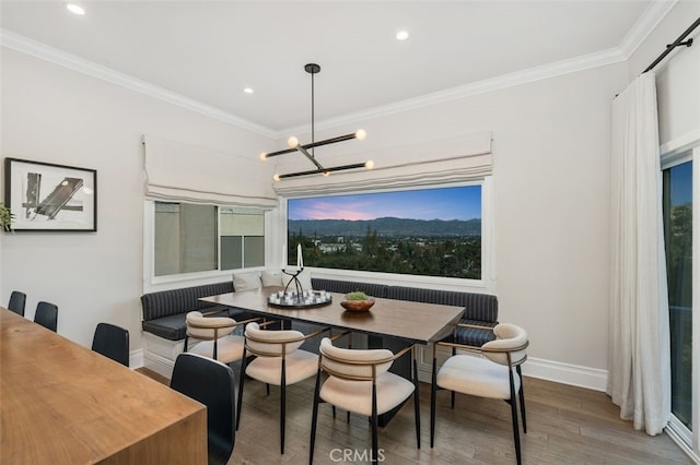 dining area with breakfast area, hardwood / wood-style floors, crown molding, and a chandelier