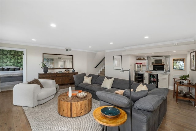 living room with ornamental molding, beverage cooler, and light hardwood / wood-style floors