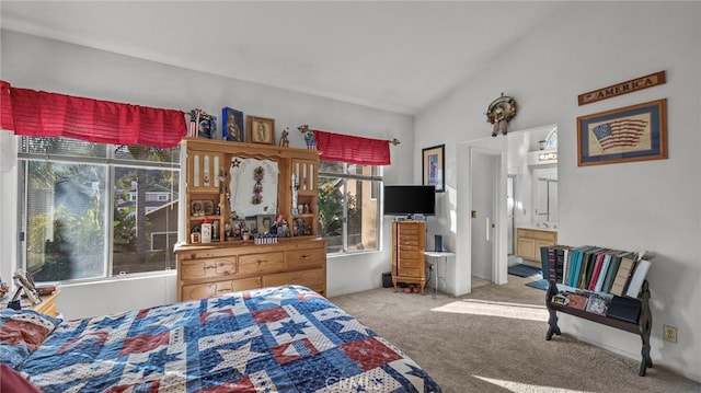 carpeted bedroom with connected bathroom, vaulted ceiling, and multiple windows