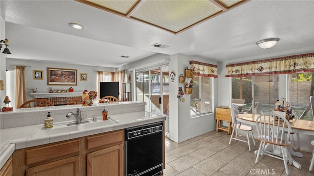 kitchen featuring a healthy amount of sunlight, tile countertops, dishwasher, and light tile patterned flooring