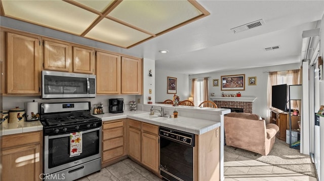 kitchen featuring appliances with stainless steel finishes, tile counters, a fireplace, light tile patterned flooring, and kitchen peninsula