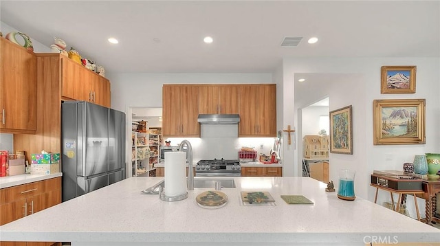 kitchen featuring fridge, sink, stainless steel stove, and a spacious island