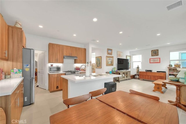 kitchen with an island with sink, appliances with stainless steel finishes, sink, and a breakfast bar area