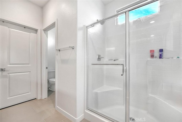 bathroom with tile patterned flooring, a shower with shower door, and toilet