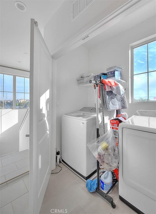 laundry area featuring washing machine and clothes dryer, a healthy amount of sunlight, and light tile patterned floors