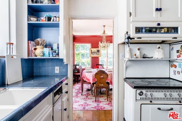 kitchen featuring tasteful backsplash, an inviting chandelier, tile countertops, hardwood / wood-style floors, and white cabinets