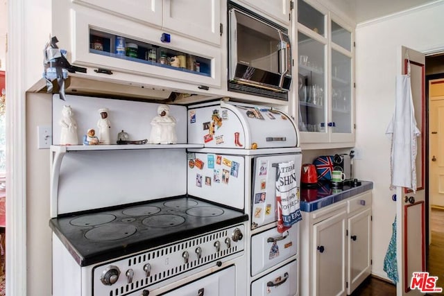 kitchen featuring tile countertops, white cabinetry, and stainless steel microwave