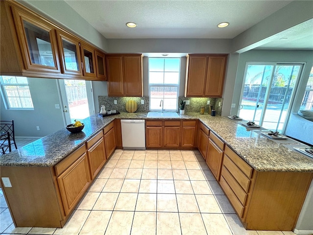 kitchen featuring sink, dishwasher, stone counters, decorative backsplash, and kitchen peninsula