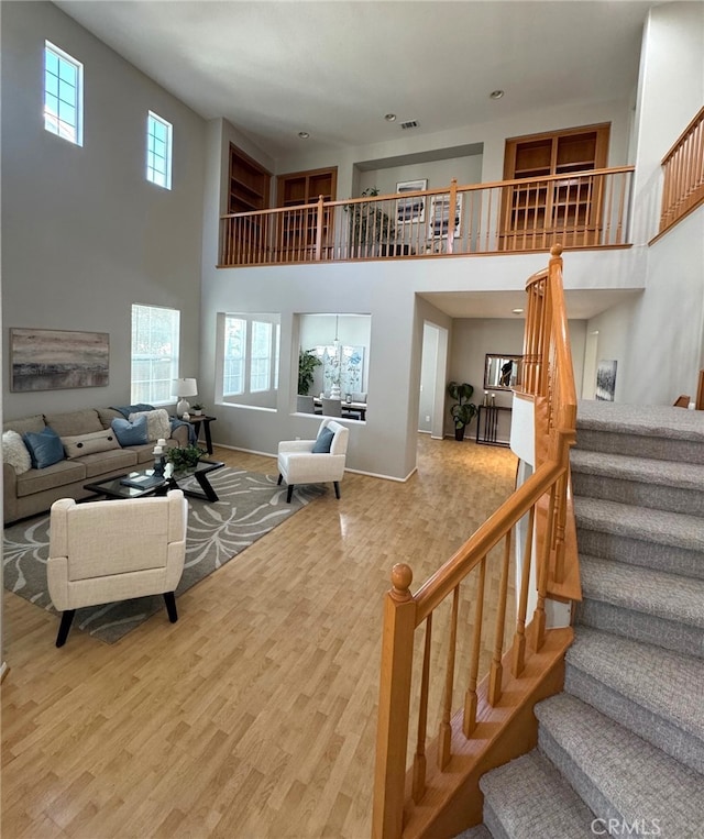 living room with a towering ceiling, wood-type flooring, and plenty of natural light