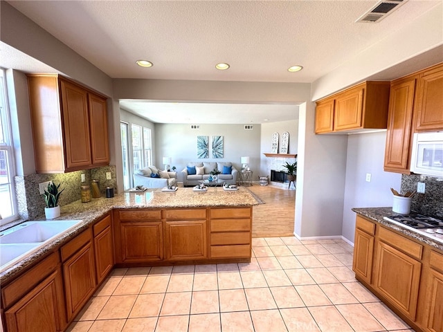 kitchen with light tile patterned floors, white appliances, a textured ceiling, decorative backsplash, and kitchen peninsula