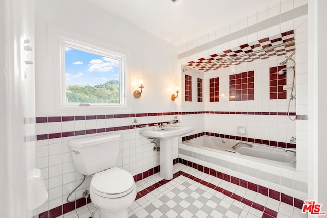 bathroom with sink, tile walls, tile patterned flooring, a relaxing tiled tub, and toilet