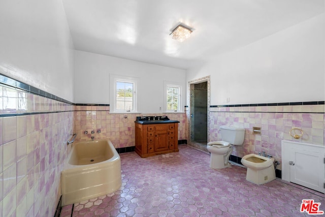 bathroom featuring tile patterned floors, toilet, tile walls, a bidet, and a tub