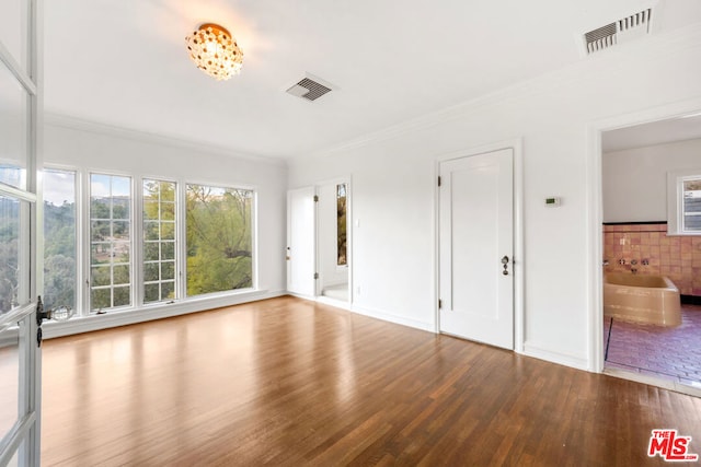 interior space with hardwood / wood-style flooring, connected bathroom, and crown molding