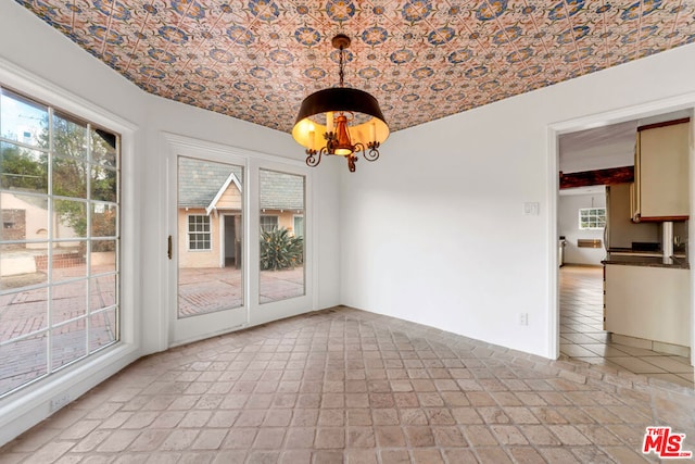 unfurnished dining area featuring a healthy amount of sunlight, brick ceiling, and a chandelier