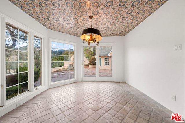 unfurnished dining area featuring brick ceiling, lofted ceiling, and a notable chandelier