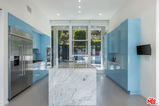 kitchen featuring appliances with stainless steel finishes, blue cabinetry, and light stone counters