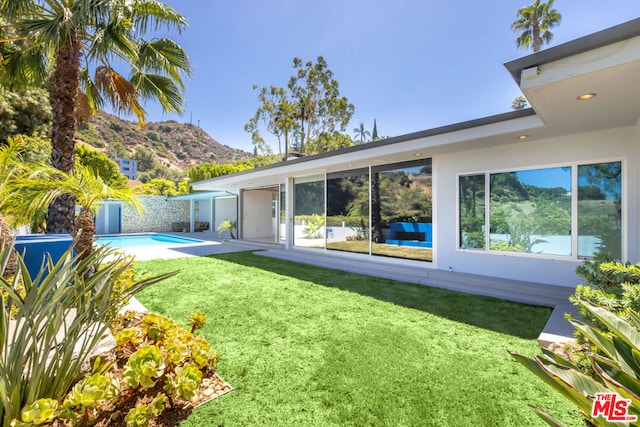 rear view of house featuring a patio, a mountain view, and a lawn