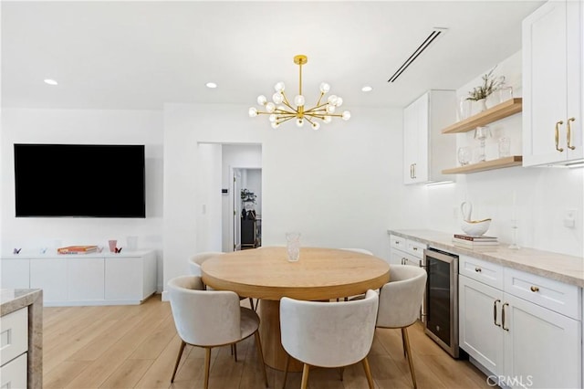 dining space featuring wine cooler, bar area, light hardwood / wood-style flooring, and a notable chandelier