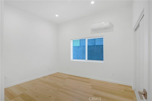 unfurnished room with a wall mounted air conditioner and hardwood / wood-style floors